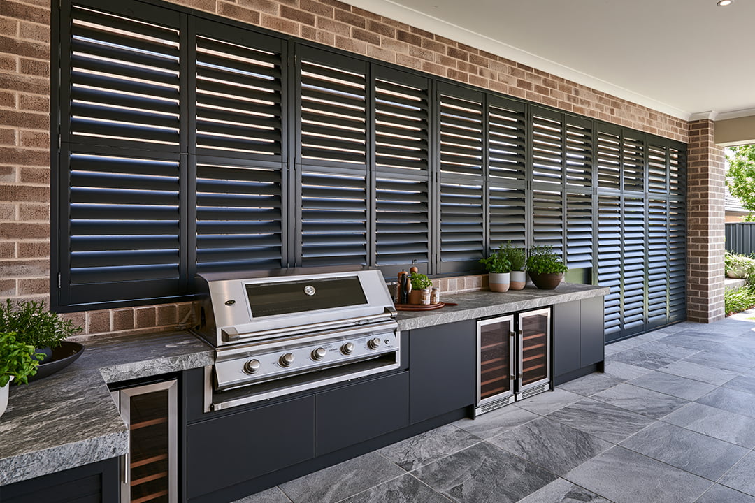 Charcoal aluminium outdoor shutters over an outdoor kitchen and BBQ area