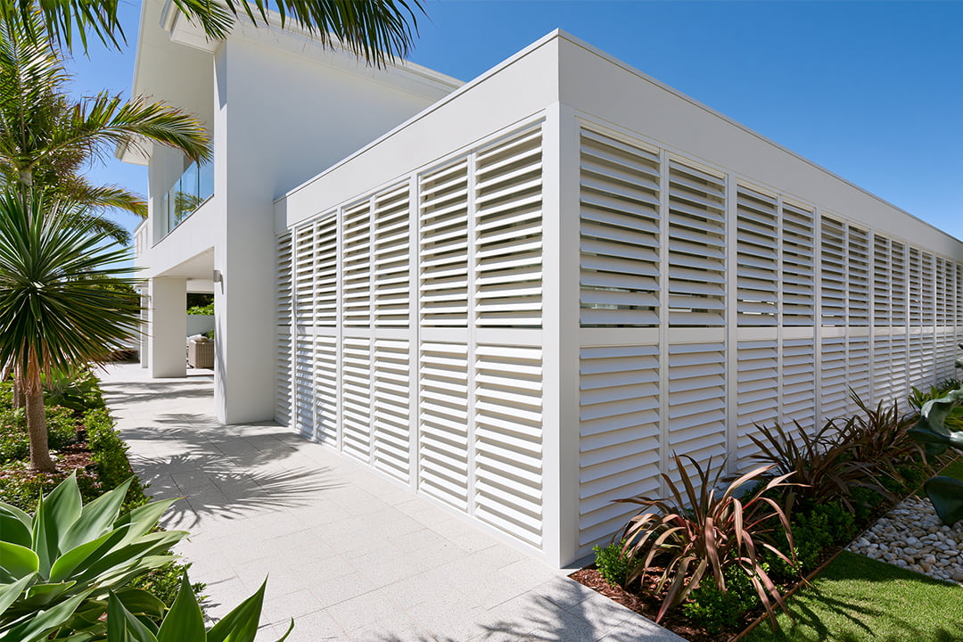 White aluminium shutters wrapping around a home's facade